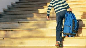 Student carries heavy backpack up stairs