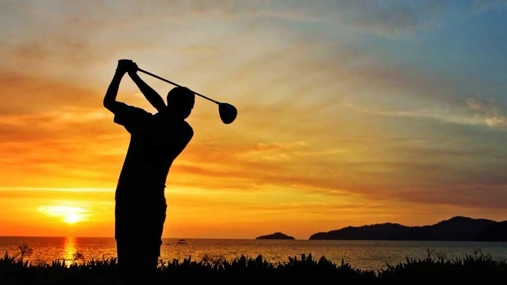 Man golfing at sunset