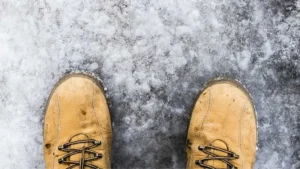 Person wearing boots while standing on snowy ice