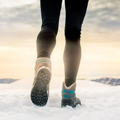 Person wearing snow boots walks in the snow