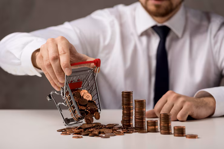 Man in white shirt and black tie dumps pennies from mini shopping cart onto table