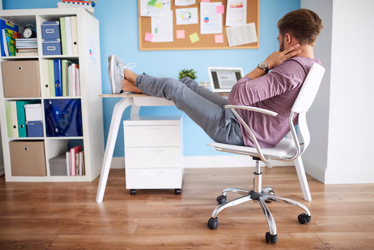 Man sits at work desk with legs up on table