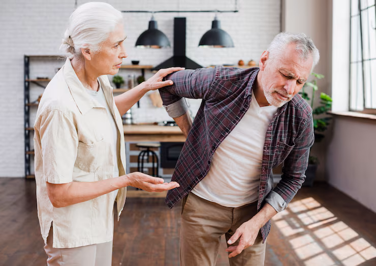 Older man experiences back pain as wife looks on concerned