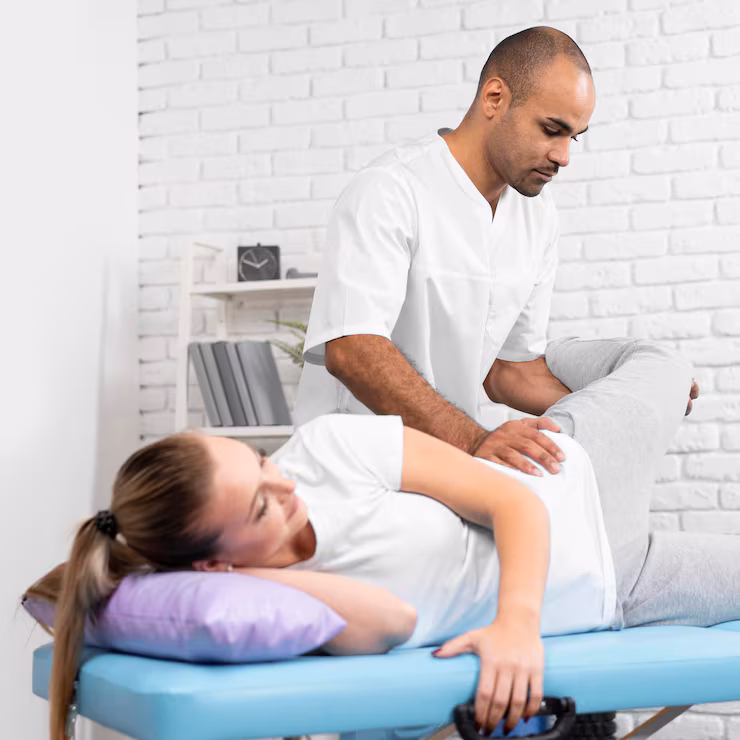 Therapist examines female patient's leg and hip