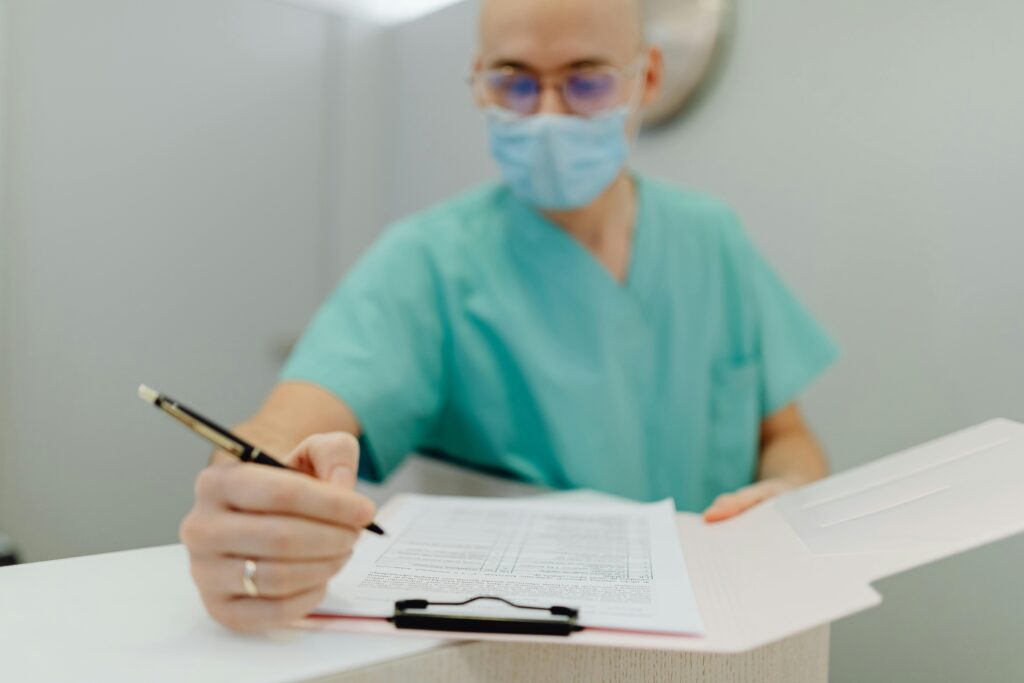 Healthcare provider in scrubs and mask fills out paperwork