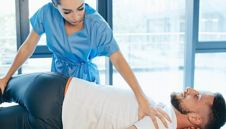 Female chiropractor adjusts male patient during treatment