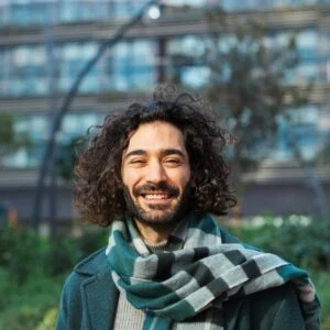 Man in green jacket and striped scarf smiles