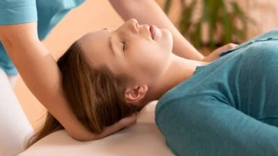 Chiropractor adjusts neck of young female patient