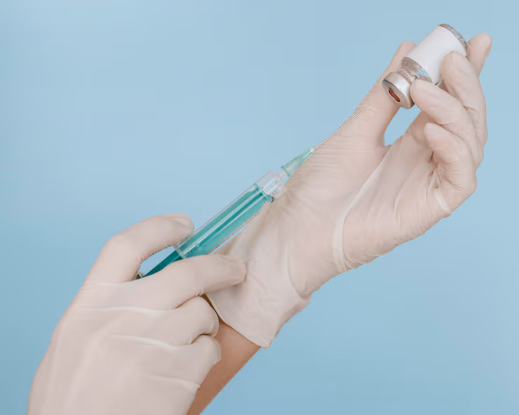 Provider wearing medical gloves holds syringe with vaccine bottle