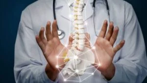 Doctor in white lab coat places hands in front of 3D spine model
